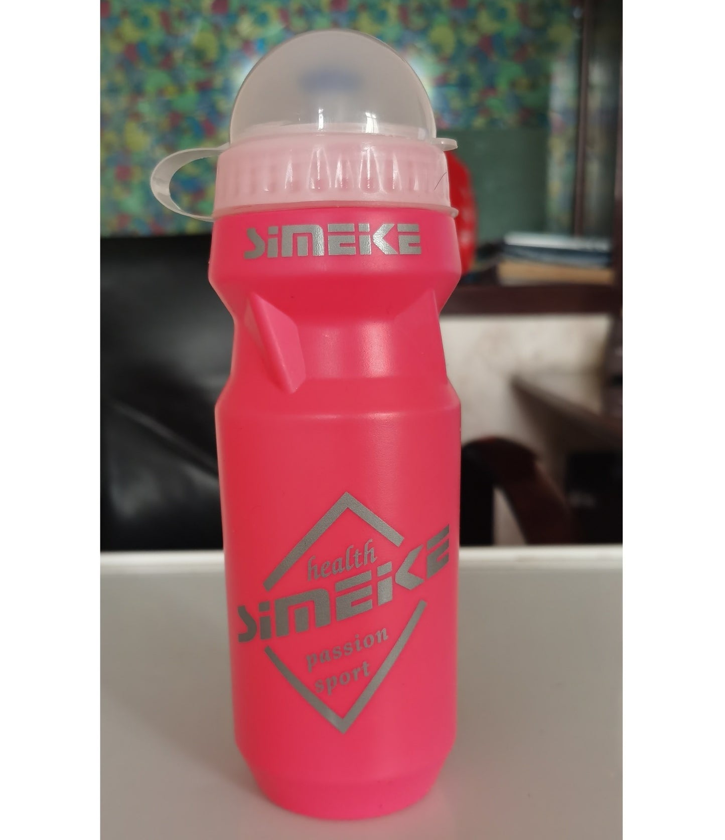 Pink cycling water bottle with a transparent cap on a blurred background