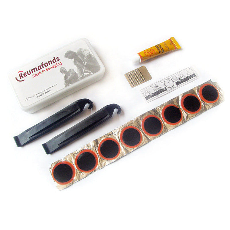 Collection of bicycle repair tools including a tin, lever, and patches on a white background