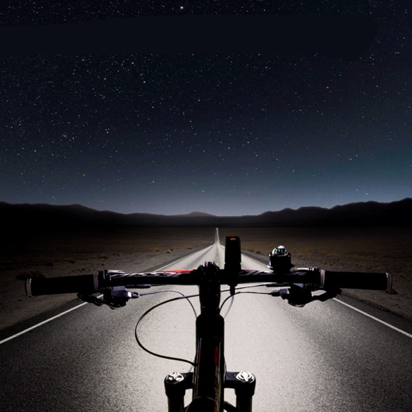 Bicycle handlebars with a road and starry night sky in the background