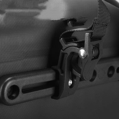 Close-up of a black bicycle pannier attachment clip on a dark background
