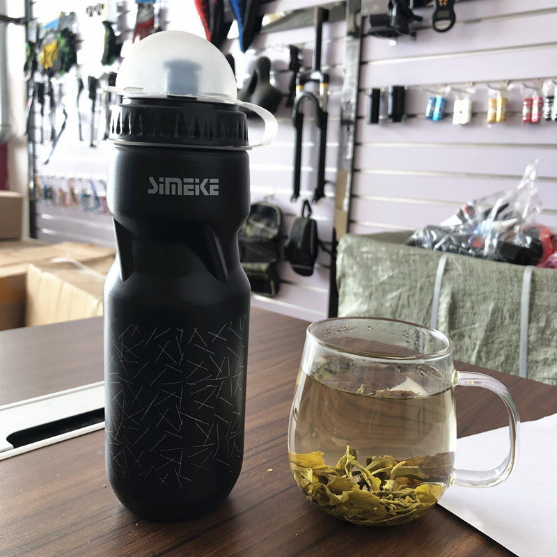 Black bicycle water bottle with black cap on a wooden table