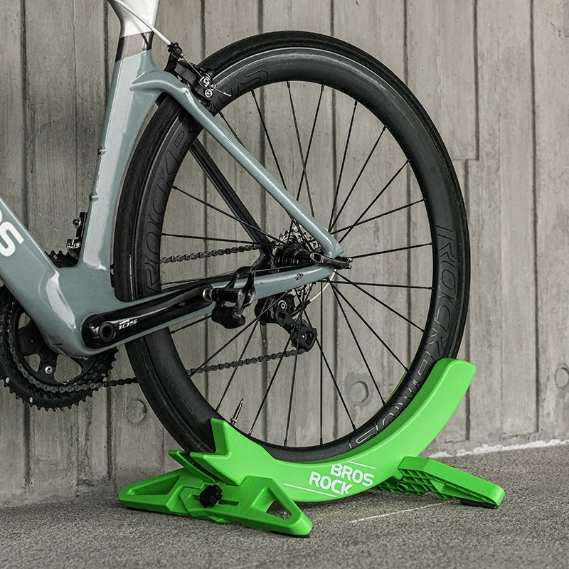Bicycle wheel on a green bike stand against a wooden background