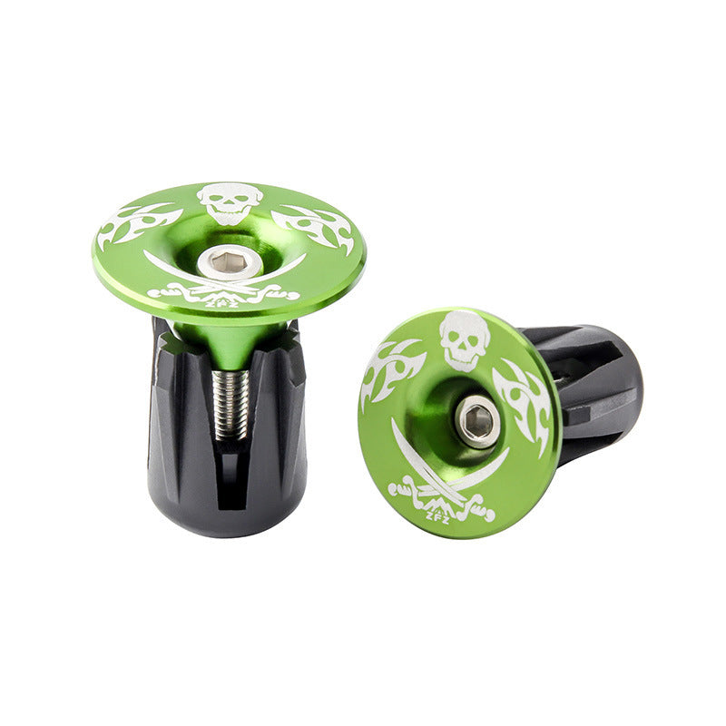 Two green metal handlebar ends with skull designs on a white background