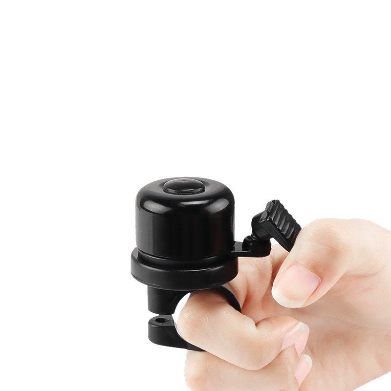 Black bicycle bell held by a hand on a white background