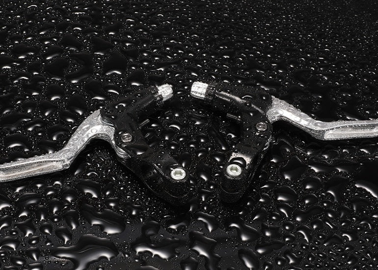 Close-up of Bicycle Brake Levers with water droplets on a black background