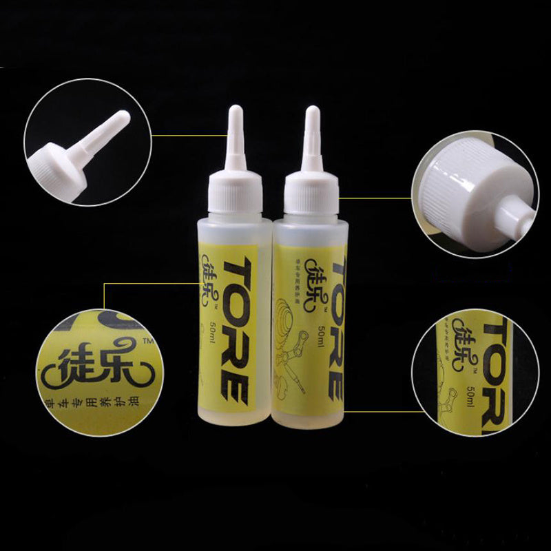 Two bottles of Tore Bicycle Chain Oil with close-up details on a black background