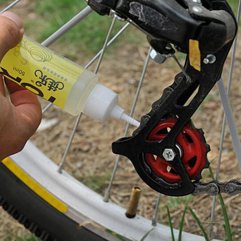 Person applying lubricant to a bicycle chain and gear system