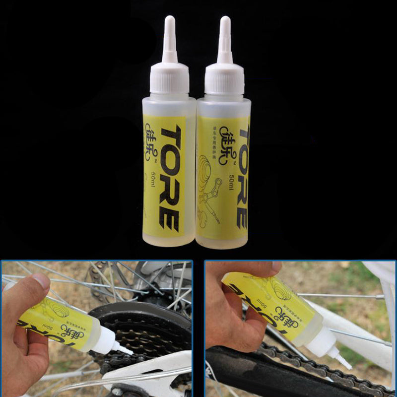 Two bottles of TORE chain lube with application on a bicycle chain.
