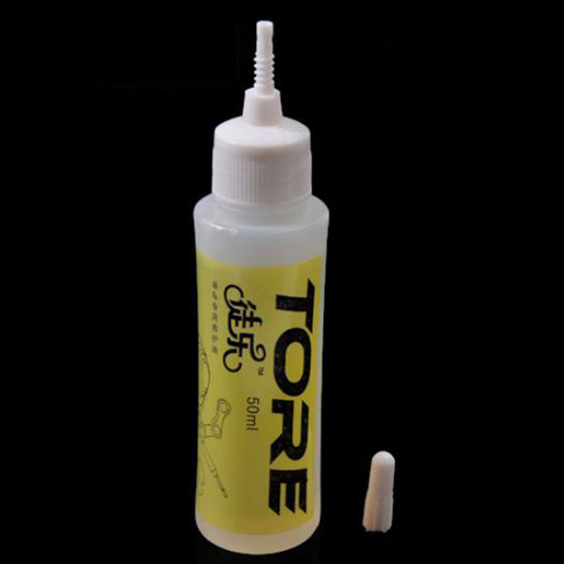 Bottle of TORE Bicycle Chain Oil with a white cap on a black background