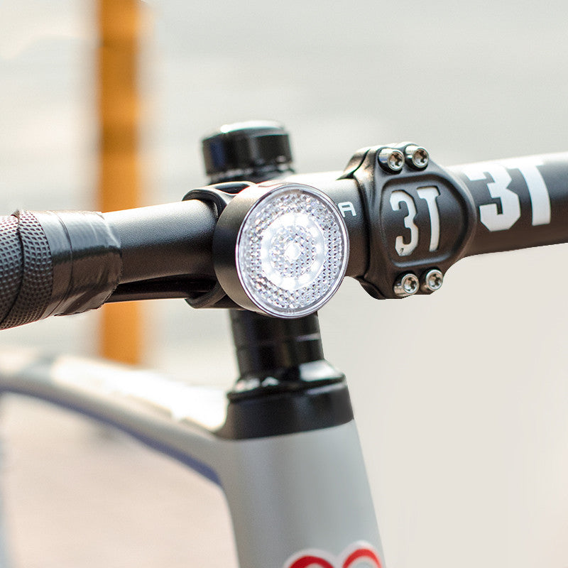 Close-up of a bicycle handlebar with a light attached, featuring the number '37'.
