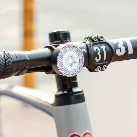 Close-up of a bicycle handlebar with a light attached, featuring the number '37'.