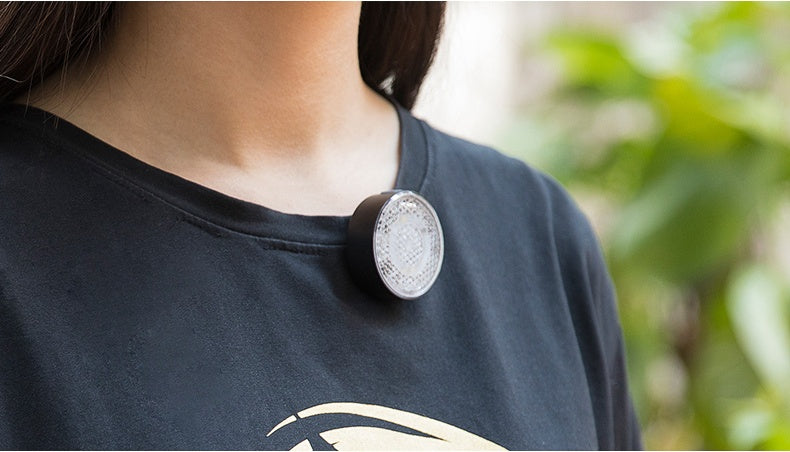 Person wearing a black shirt with a LED Light on a blurred green background