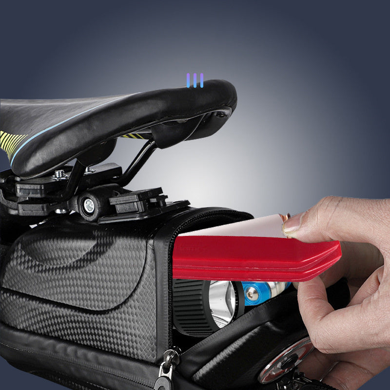 Hand opening a black bicycle saddlebag with a red tool on a dark background