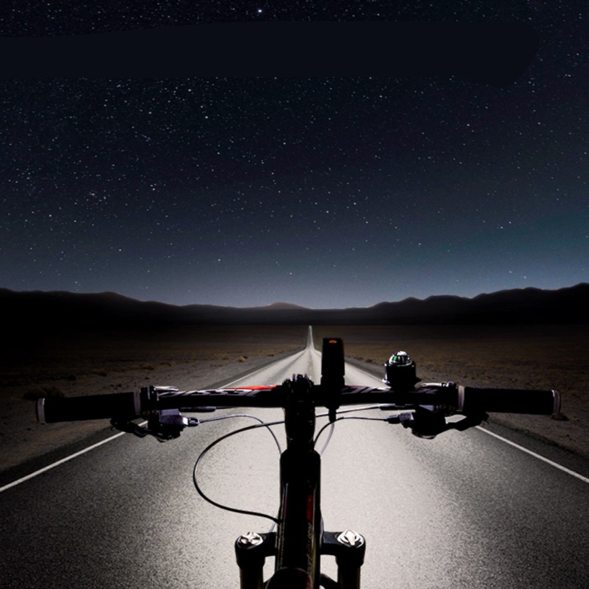 Bicycle handlebars with a road and starry night sky in the background