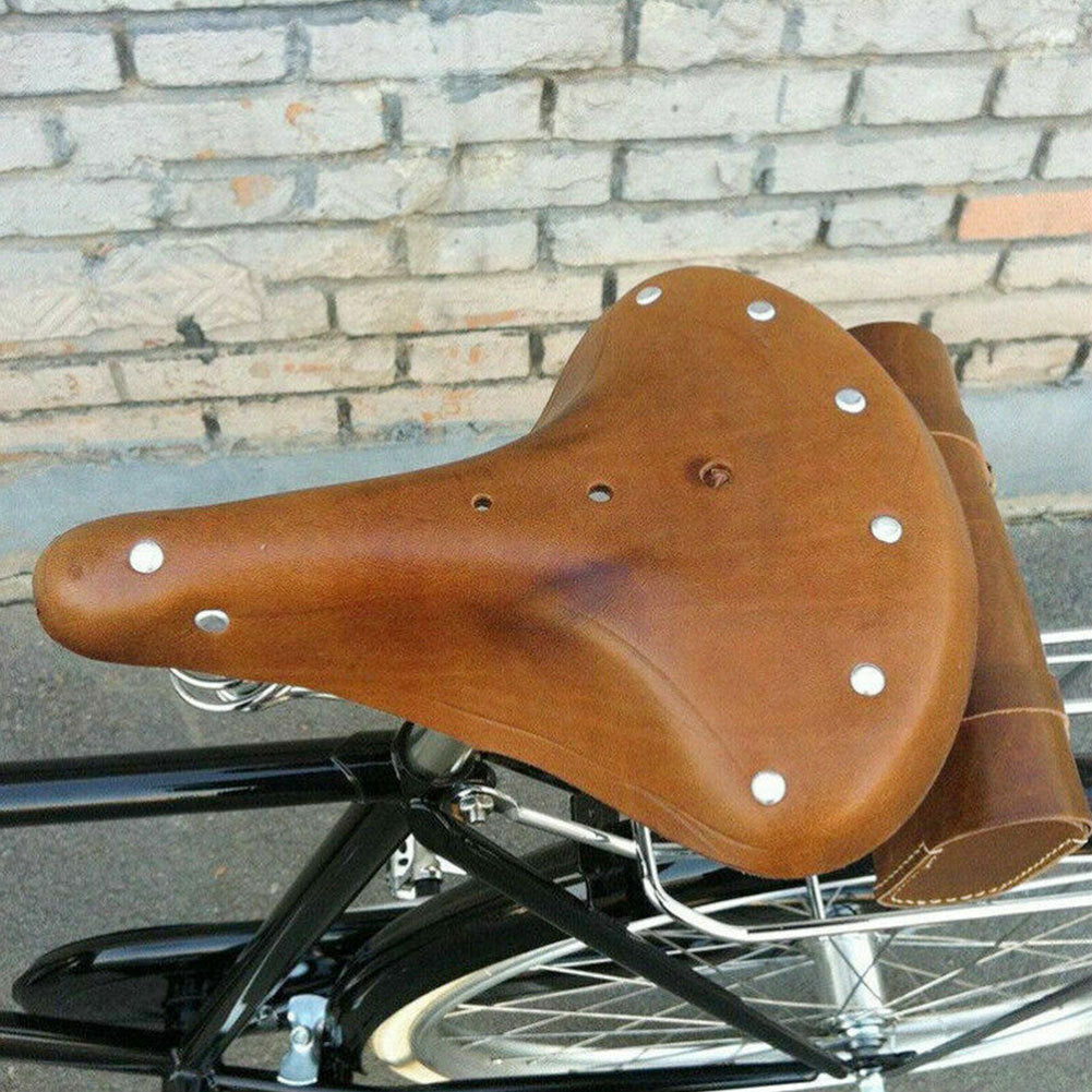 Brown leather bicycle saddle on a bike with a brick wall background