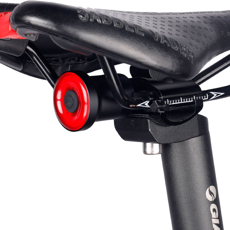 Close-up of a bicycle saddle with red seat post and black frame on a white background