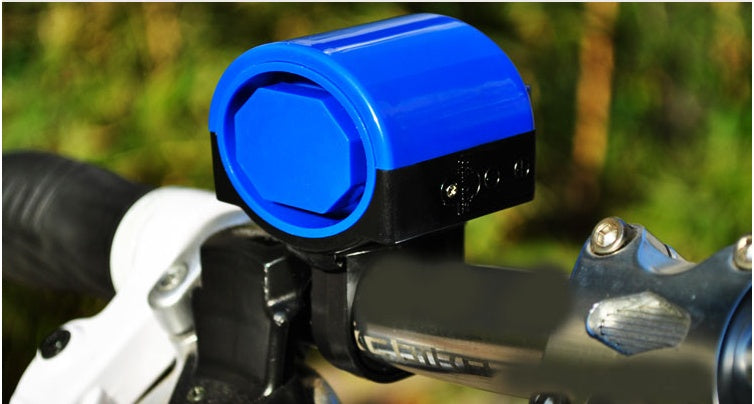 Blue electric bicycle horn mounted on a handlebar with a blurred natural background