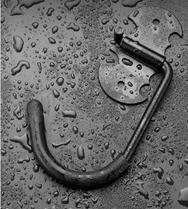 Black metal bicycle storage hook on a textured surface with water droplets