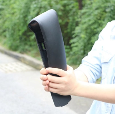 Person folding a black mountain bicycle mudguard against a blurred green outdoor background