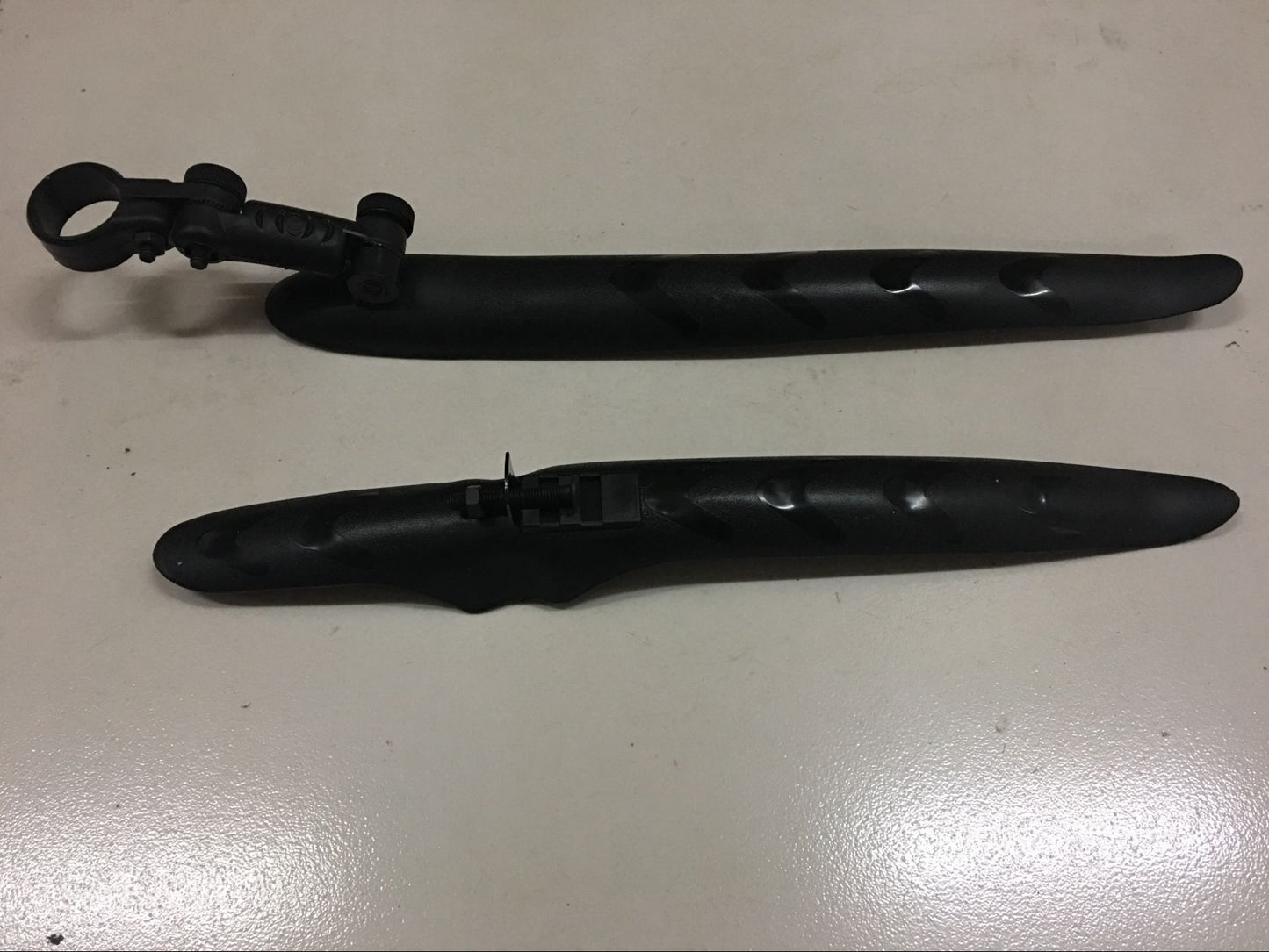 Two black bicycle mudguards on a white surface