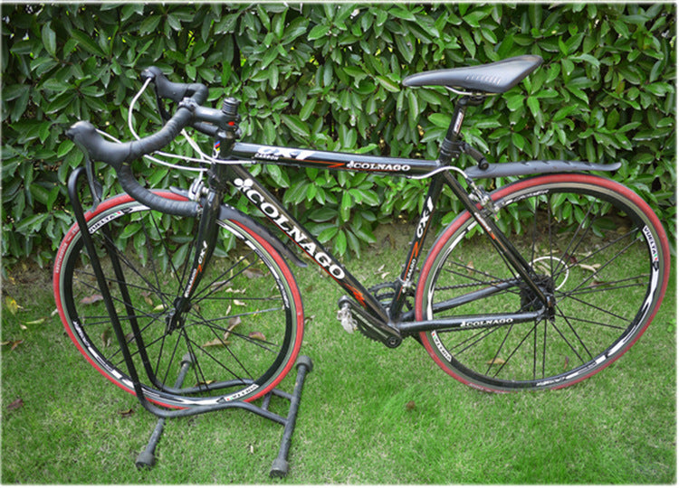 Colnago bicycle on a stand with detachable mudguards against a green hedge background