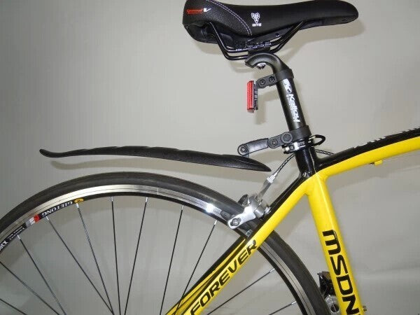 Yellow bicycle with black seat and black rear fender against a plain background