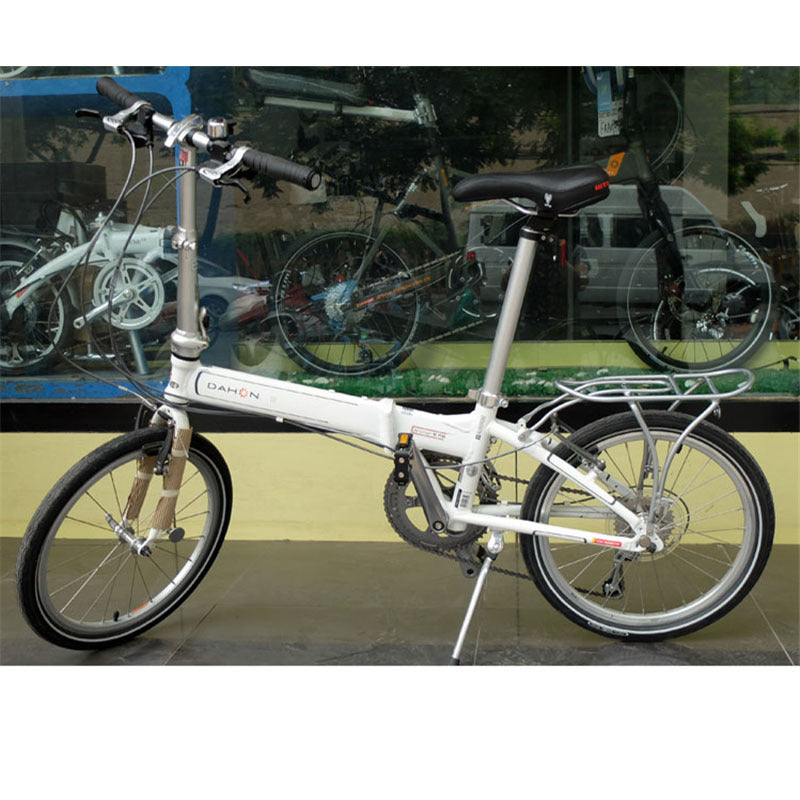White folding bicycle with 'Gazelle' branding and rear bicycle rack on a reflective surface.