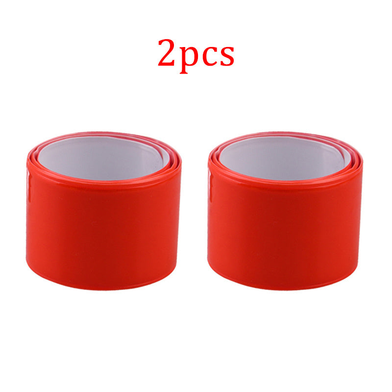 Two red reflective cycling leg bands with a white center on a white background
