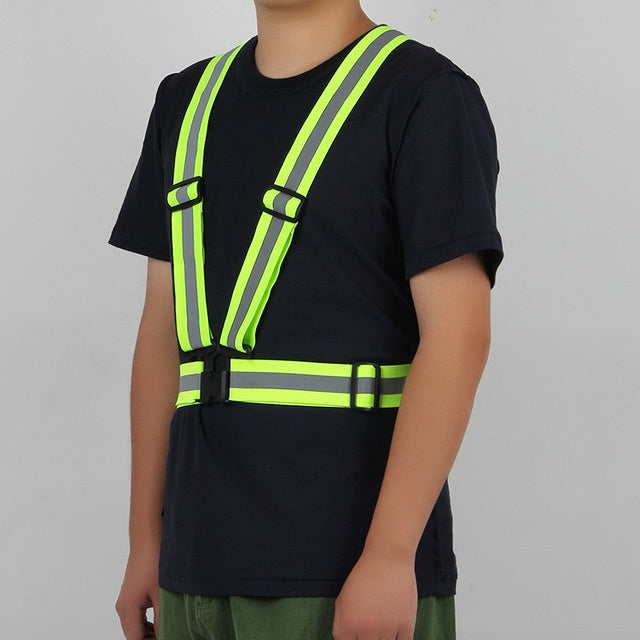 Person wearing a black shirt with a high-visibility safety vest on a gray background