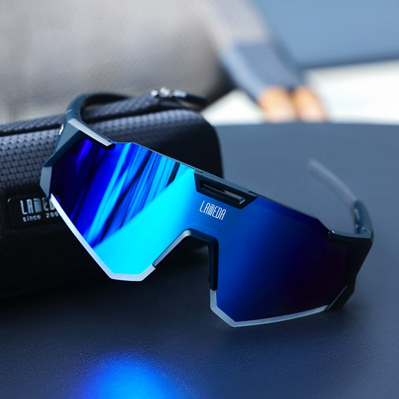 Blue cycling sunglasses with a reflective lens on a blurred background