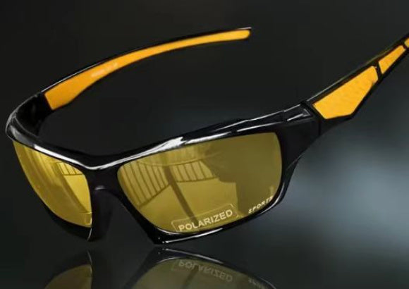 Cycling sunglasses with yellow lenses and black frame on a reflective surface
