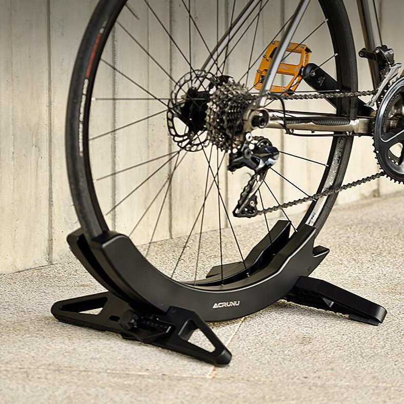 Bicycle supported in a black stand with a wooden floor background