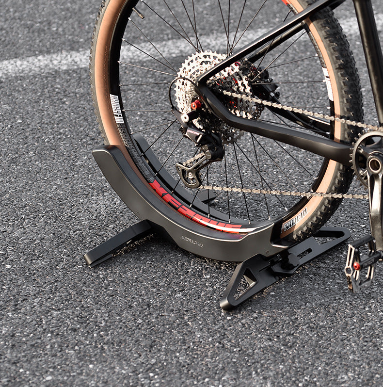 Bicycle on a stand with a close-up of the wheel and chain on an asphalt surface