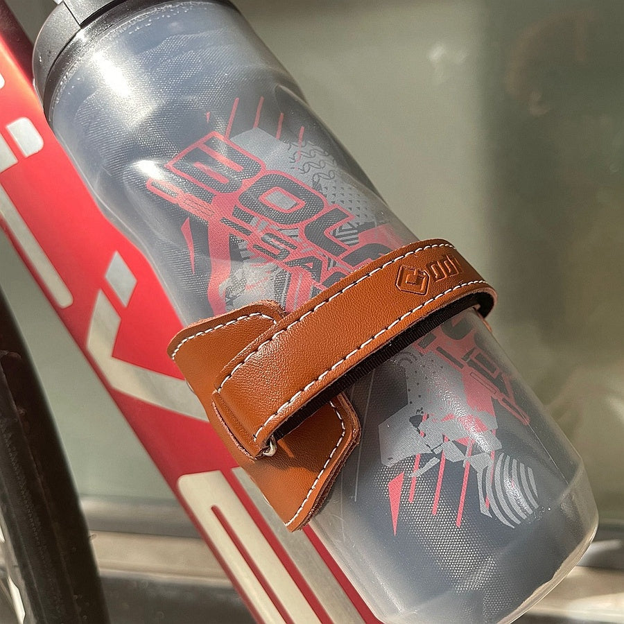 Clear water bottle in a Retro Cowhide Bicycle Bottle Holder/Cage attached to a red and white bicycle.