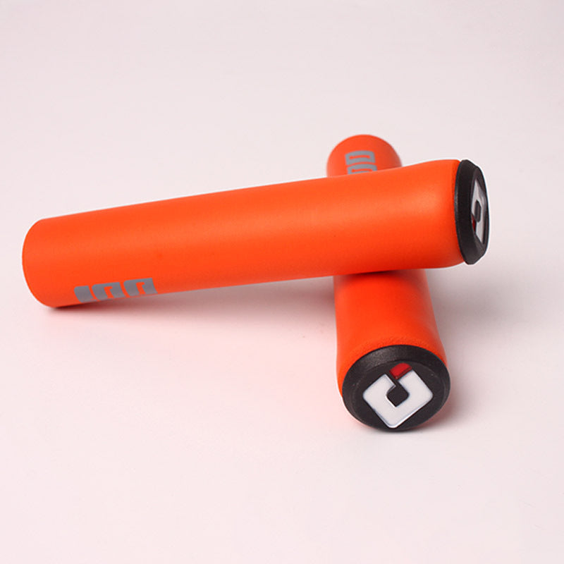 Orange silicone bicycle handlebar grips with black ends on a light pink background