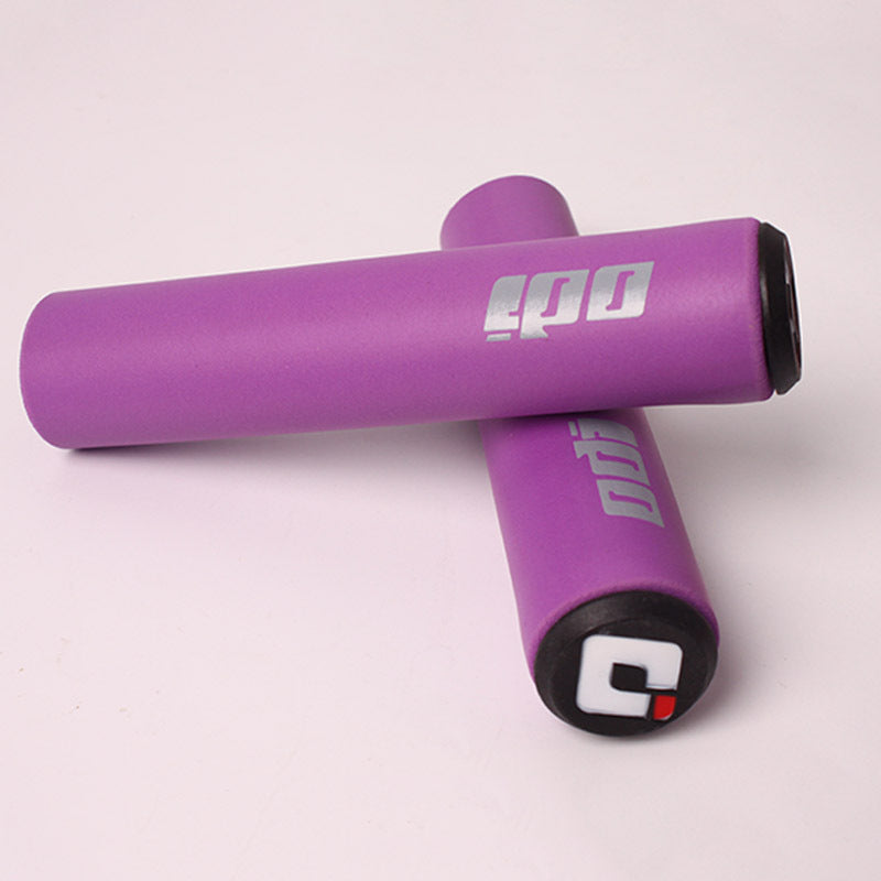 Purple silicone bicycle handlebar grips with visible branding on a light pink background
