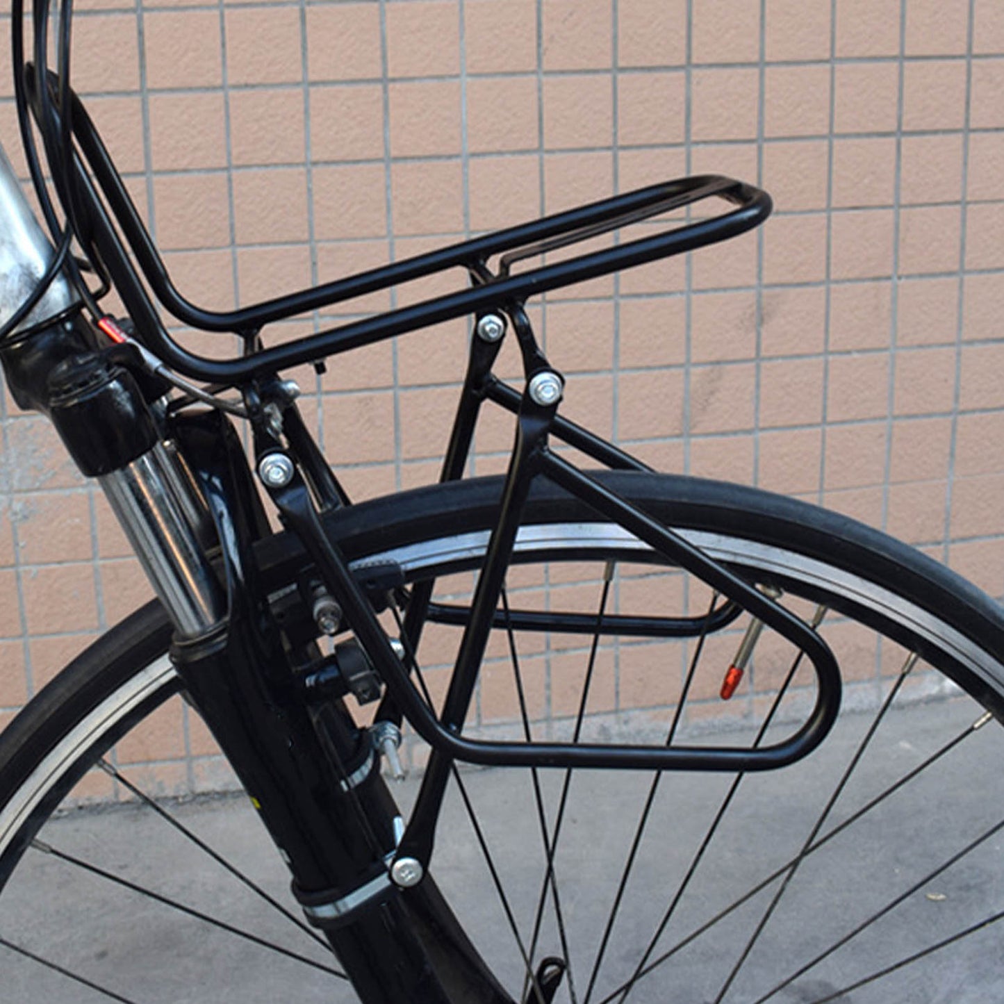 Black steel bicycle rack attached to a bicycle against a tiled wall.