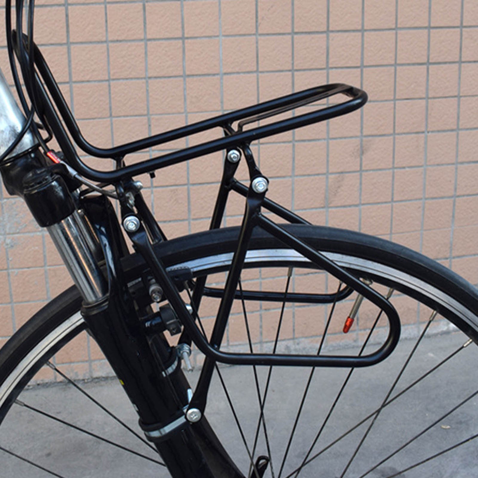 Black steel bicycle rack attached to a bicycle against a tiled wall.
