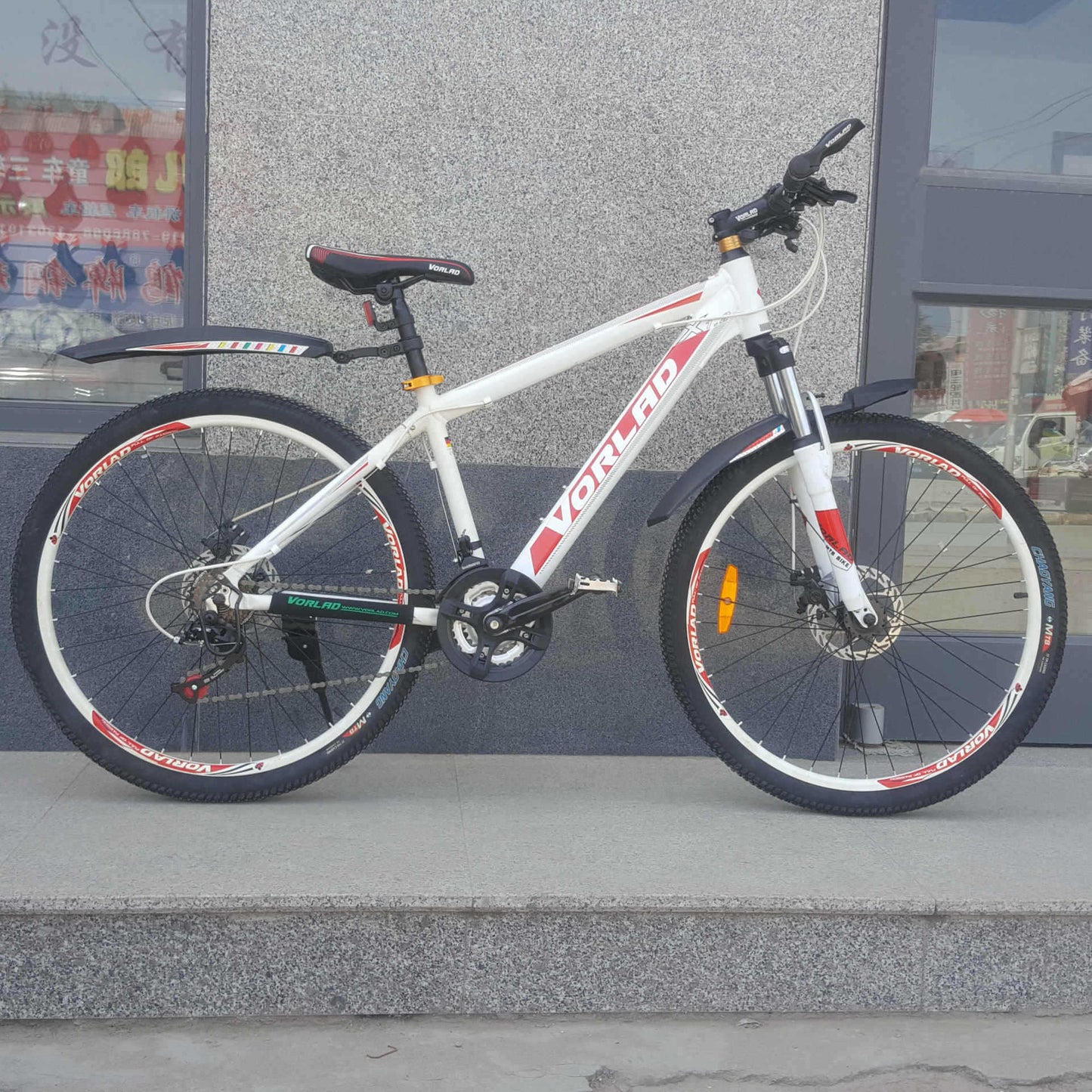 White bicycle with red and black details and front and rear detachable mudguards on a concrete surface.