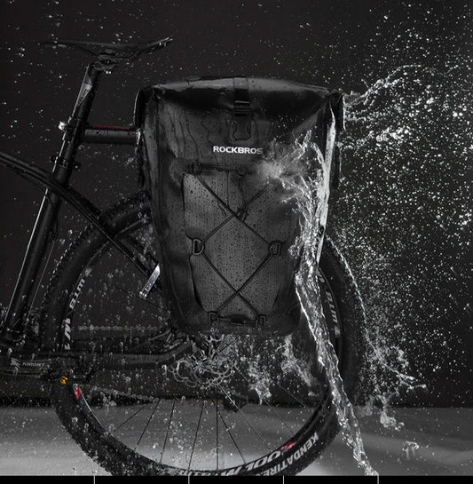 Bicycle with a backpack labeled 'RockBros' splashing through water at night.