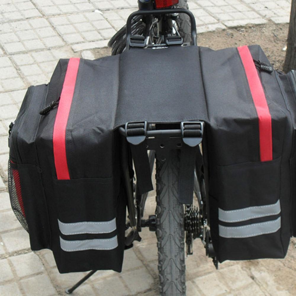 Black bicycle panniers with red stripes and white reflective stripes attached to a bike.
