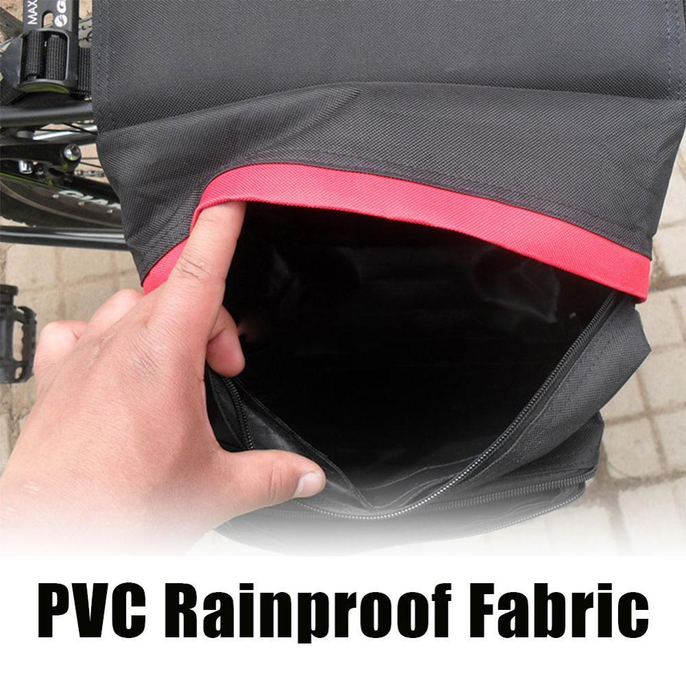Hand opening a black bag bicycle pannier with pink trim, highlighting PVC rainproof fabric.