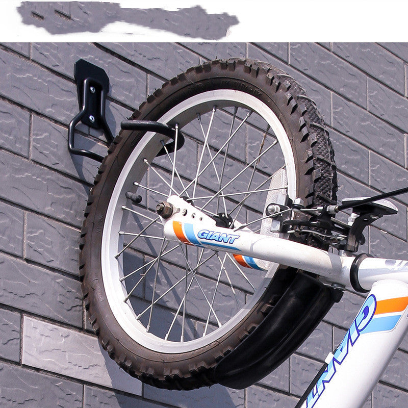 Bicycle attached to a wall-mounted bike holder against a gray brick wall.